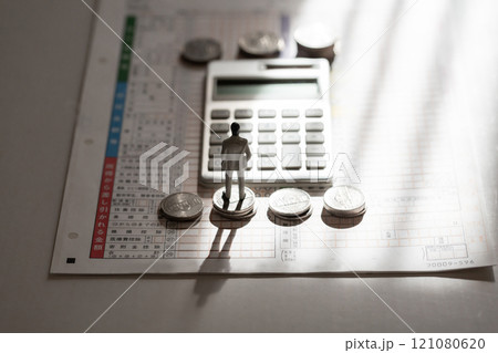 確定申告 お金のイメージ 影の中の男性のミニチュア、電卓、硬貨と確定申告書 121080620