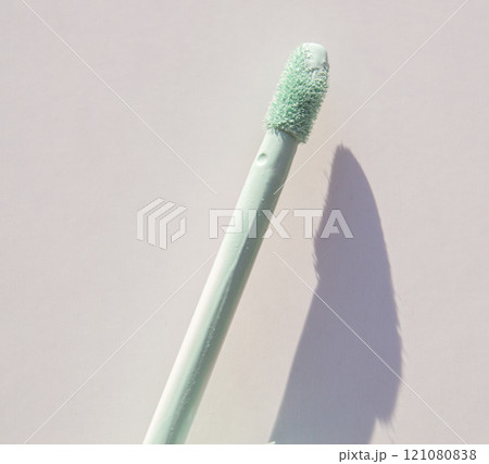Close-up of a brush of green concealer for correcting skin imperfections, on a white background 121080838