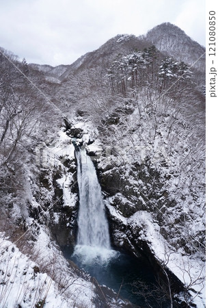 曇天の冬空と雪の積もった山を背景に流れ落ちる秋保大滝の冬景色 121080850
