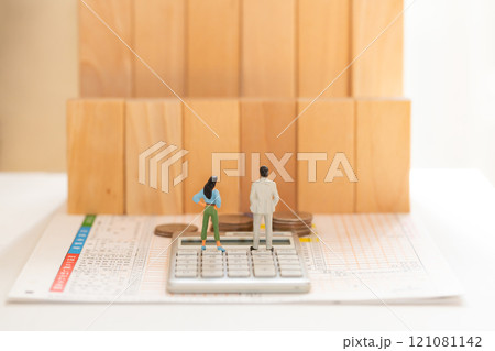 確定申告 年収の壁 お金のイメージ  確定申告書と計算機の上に立つ男女のフィギュア 121081142