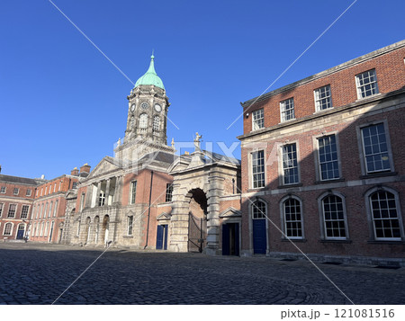 The clock tower of Dublin Castle stands tall with its distinctive green dome and clock face, set against a blue sky with scattered clouds 121081516