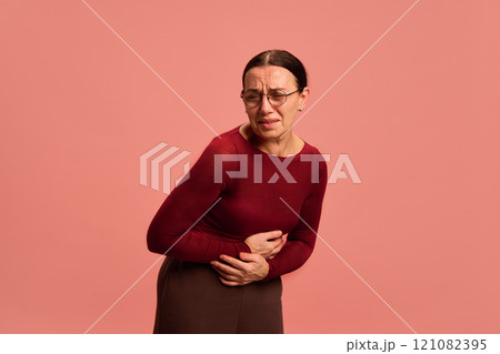 Female health. Woman sick unhappy holding uterus pain, reproductive system against pastel peach background. 121082395