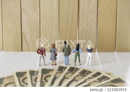 年収の壁 お金のイメージ  積み木の壁を前にする男女のフィギュア 121082653