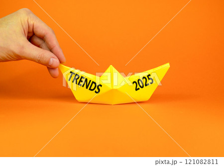 Planning trends 2025 new year symbol. Concept words Trends 2025 on beautiful yellow paper boat. Beautiful orange paper background. Businessmen hand. Business trends 2025 new year concept. Copy space. 121082811