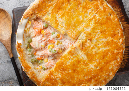 Tasty creamy salmon vegetables pot pie with crispy puff crust closeup on the baking dish. Horizontal top view 121084521