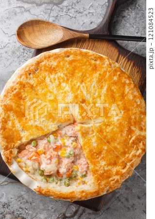 Creamy salmon pot pie are a delicious, easy and hearty feast full of flavor closeup on the baking dish. Vertical top view 121084523