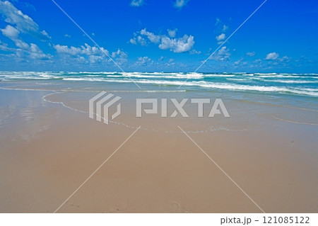 Wide sandy beach on the Golden Coast, Australia, with clear blue skies and gentle ocean waves 121085122