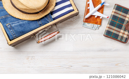 A travel bag with clothes, sun hat, flip flops, and a camera A travel bag with clothes, sun hat, flip flops, and a camera 121086042