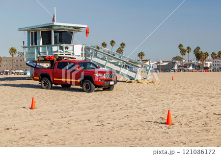 Classic lifeguard tower paired with a rescue vehicle parked nearby on a sandy beach 121086172