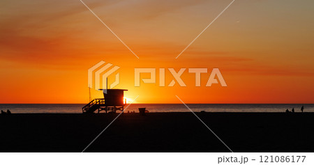 Los Angeles beach at sunset, featuring a lifeguard tower silhouette against a glowing orange and purple horizon Los Angeles beach at sunset, featuring a lifeguard tower silhouette against a glowing orange and purple horizon 121086177