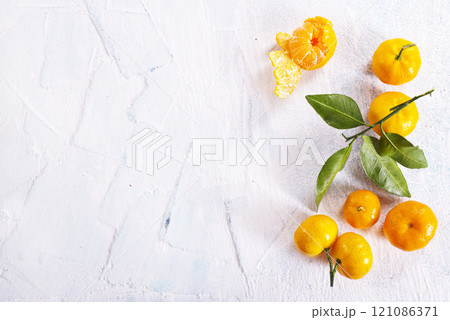 Orange fruit with green leaves on the white wood. 121086371