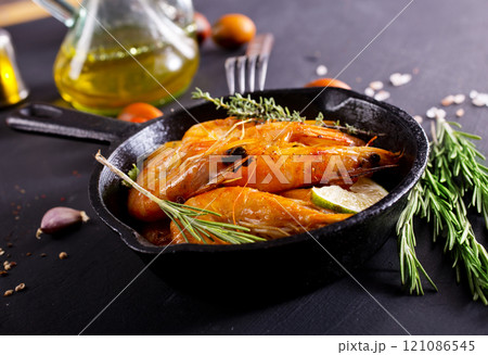 Grilled shrimps with greens and garlic in a pan 121086545