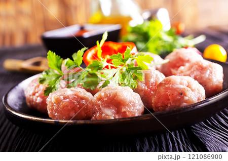 Raw meatballs on plate on a table, close up 121086900