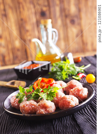 Raw meatballs on plate on a table, close up 121086901