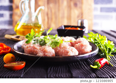 Raw meatballs on plate on a table, close up Raw meatballs on plate on a table, close up 121086905