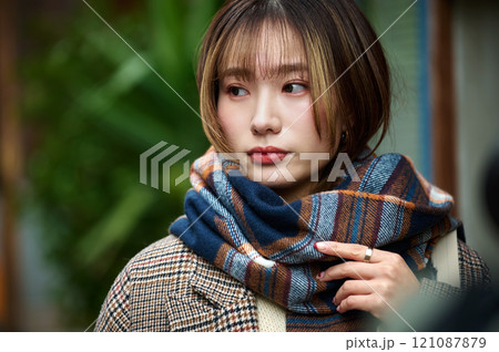 スマホを持つマフラーを巻いた冬服の若い女性 スマホを持つマフラーを巻いた冬服の若い女性 121087879