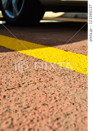 Asphalt concrete road with yellow stripes and car parking area 121088137