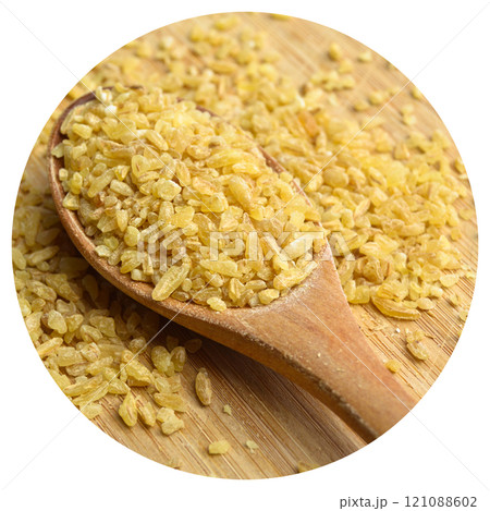 Cracked wheat daliya grains in wooden spoon, on bamboo cutting board 121088602
