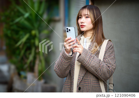 スマホを持つ冬服の若い女性 121090406