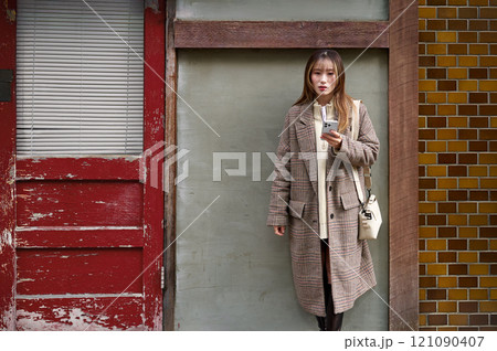 スマホを持つ冬服の若い女性 121090407