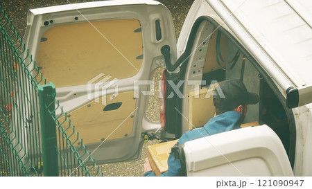 Unrecognizable French courier unloads big carton from the commercial van Unrecognizable French courier unloads big carton from the commercial van 121090947