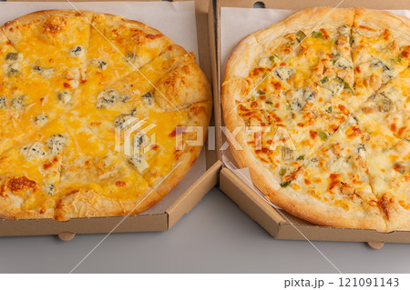 Two different pizzas in a paper box on a gray background. Pizza food delivery. 121091143
