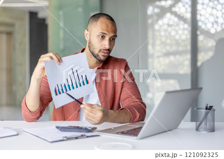 A professional individual presenting graph data while engaged in an online meeting at work. Captures themes of communication, analysis, and productivity in a contemporary office setting. 121092325