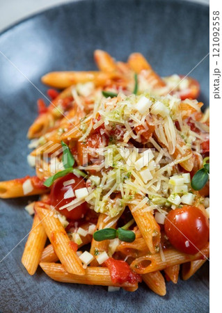 Penne pasta being served with tomato sauce, cheese, and basil Penne pasta being served with tomato sauce, cheese, and basil 121092558