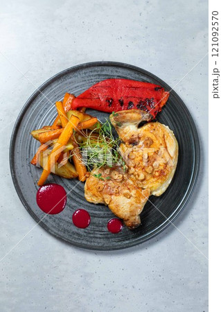 Roasted chicken breast with potatoes, carrots, red pepper and sauce on a plate Roasted chicken breast with potatoes, carrots, red pepper and sauce on a plate 121092570