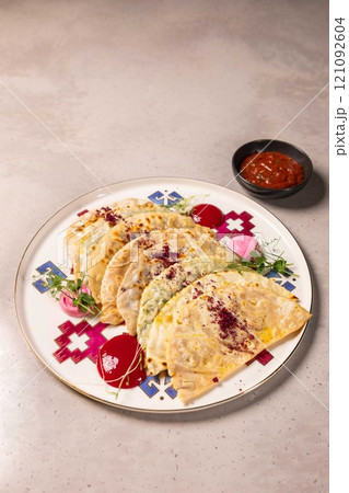 Delicious qutab lying on plate with sauce and greens Delicious qutab lying on plate with sauce and greens 121092604