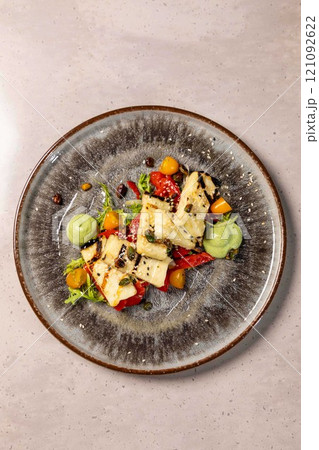 Grilled halloumi cheese salad with vegetables and pesto dressing Grilled halloumi cheese salad with vegetables and pesto dressing 121092622