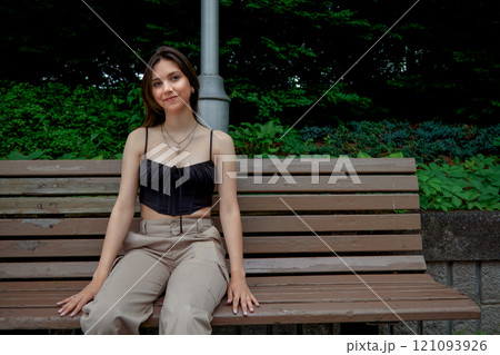 Young Woman Sitting on a Park Bench 121093926