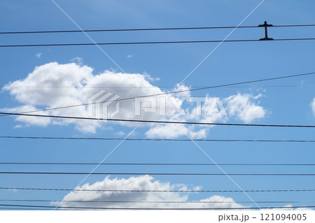 Trolleybus wires against the background of white clouds and blue sky, urban public transport. Trolleybus wires against the background of white clouds and blue sky, urban public transport. 121094005