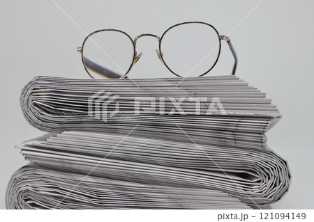 Rolled up stack of fresh newspapers and glasses, news, printed background. Rolled up stack of fresh newspapers and glasses, news, printed background. 121094149