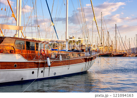 Group of boats docked in a harbor of Bodrum in Turkey at sunset. Scenic view of sailing yachts in cruise port and bay at dusk. Empty dockyard in Aegean sea in evening. Tourism abroad, overseas Group of boats docked in a harbor of Bodrum in Turkey at sunset. Scenic view of sailing yachts in cruise port and bay at dusk. Empty dockyard in Aegean sea in evening. Tourism abroad, overseas 121094163