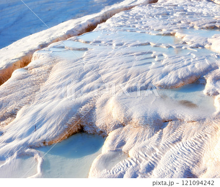 Closeup of travertine pools and terraces in Pamukkale, Turkey. Traveling abroad for vacation and tourism. Cotton castle area with carbonate mineral after flowing thermal spring water from above 121094242