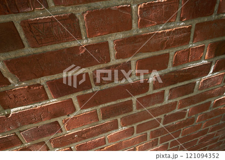 Above closeup of a wall of red brick still life. Hard solid building material with rough texture on a building in town, city or house. Concrete surface with cement lining to keep a structure intact 121094352