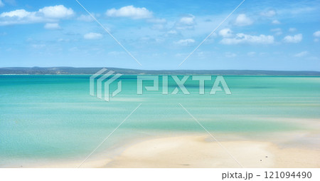 Beautiful beach landscape and horizon under cloudy blue sky copy space with calm and tranquil ocean scenery. A sea with a mountain in the background. A quiet coastal holiday or vacation by the shore 121094490