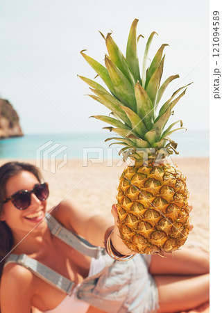 Pineapple, travel and portrait of a woman on the beach to relax on holiday or vacation during summer. Relax, smile and a happy young person with fruit on the sand by the ocean or sand for tourism Pineapple, travel and portrait of a woman on the beach to relax on holiday or vacation during summer. Relax, smile and a happy young person with fruit on the sand by the ocean or sand for tourism 121094589