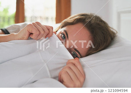 Portrait, woman and peeking in bed cover to wake up, relax and peace in home bedroom. Hiding face, morning and person in duvet for comfort, healthy rest and eyes of shy girl on pillow in Switzerland Portrait, woman and peeking in bed cover to wake up, relax and peace in home bedroom. Hiding face, morning and person in duvet for comfort, healthy rest and eyes of shy girl on pillow in Switzerland 121094594