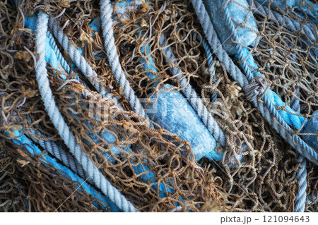 Background. Buoys and a net tangible together as fishing gear or equipment at a harbor. Closeup of blue sea markers and mesh piled, grouped, or gathered together on a boat useful for a background. 121094643