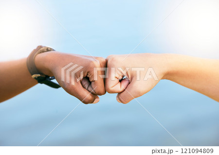 Female friends feeling supported, united and touching fists at the knuckles. Feeling motivated and ready to achieve. Closeup of two unknown people giving each other a fist bump against blue copyspac 121094809