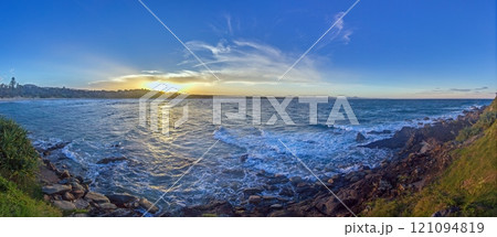 Vivid sunset over a calm ocean horizon, blending vibrant orange and blue hues, evoking serenity 121094819