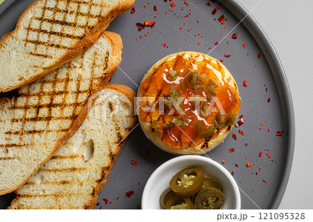 Portion of baked brie with jalapeno and toast 121095328
