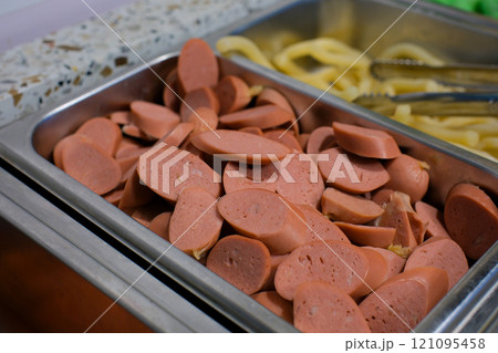 Food tray with delicious salami, pieces of sliced ham, sausage, tomatoes, salad and vegetable Meat platter with selection - Cutting sausage and cured meat on a celebratory table. 121095458