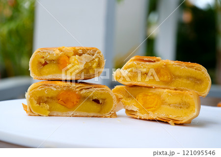 High angle view of whole and two halves chinese pastry or moon cake filled with sweet mung bean paste and salted egg yolk. 121095546