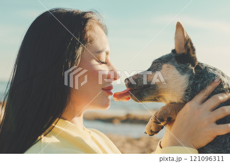 young woman in profile holding sheepdog puppy who licks her young woman in profile holding sheepdog puppy who licks her 121096311