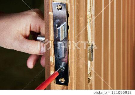 Locksmith inserts framework of mortise door lock into groove or pocket cut into edge of door. 121096912