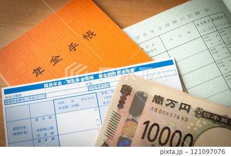 年金額改定通知書と年金手帳と一万円札　老齢厚生年金 121097076