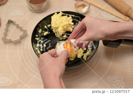 Christmas homemade baking, ingredients for baking gingerbread, woman hands breaks an egg in black bowl 121097557